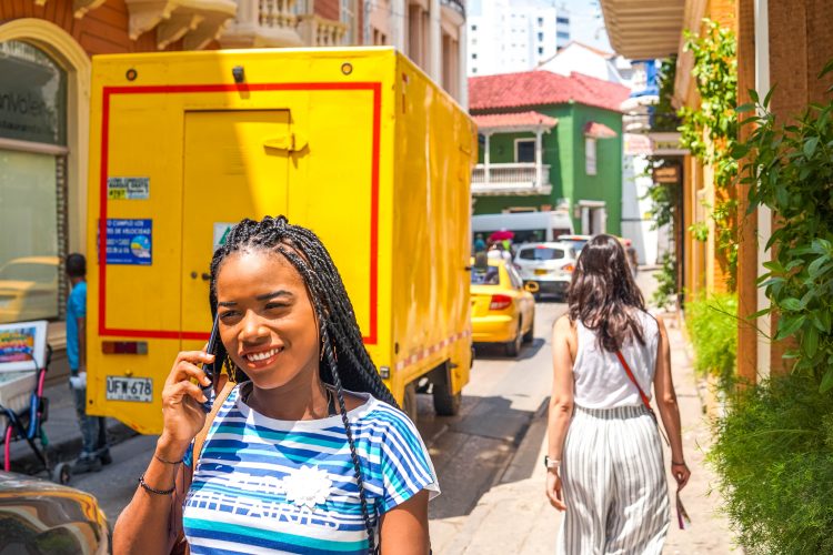 Jeune femme métisse qui marche dans la rue en téléphonant